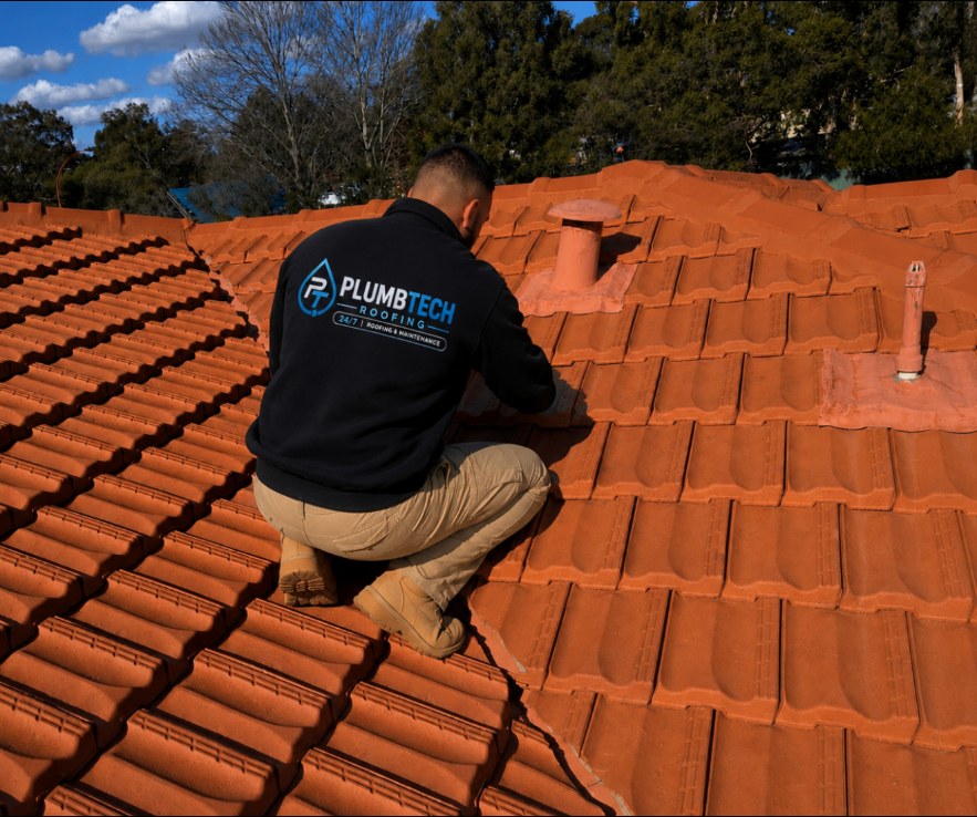 Plumbtech roofer replacing tiles on a restored terracotta roof